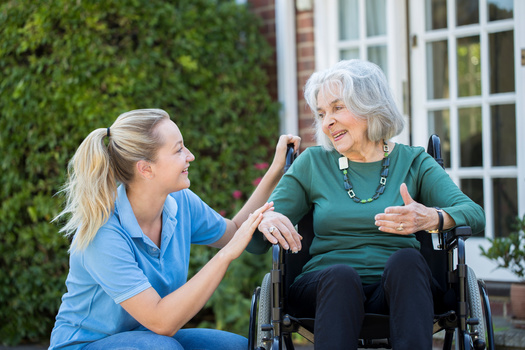 Caregiver assisting elderly woman in wheelchair.